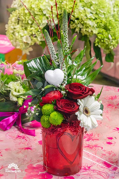 Compo de roses rouges et fleurs blanches dans un pot en verre rouge avec un coeur dessiné